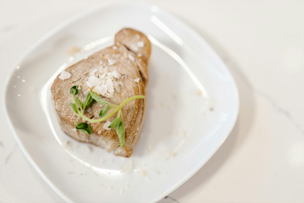 Chunk of Fried Tuna Fish Meat Served with Herbs on White Plate